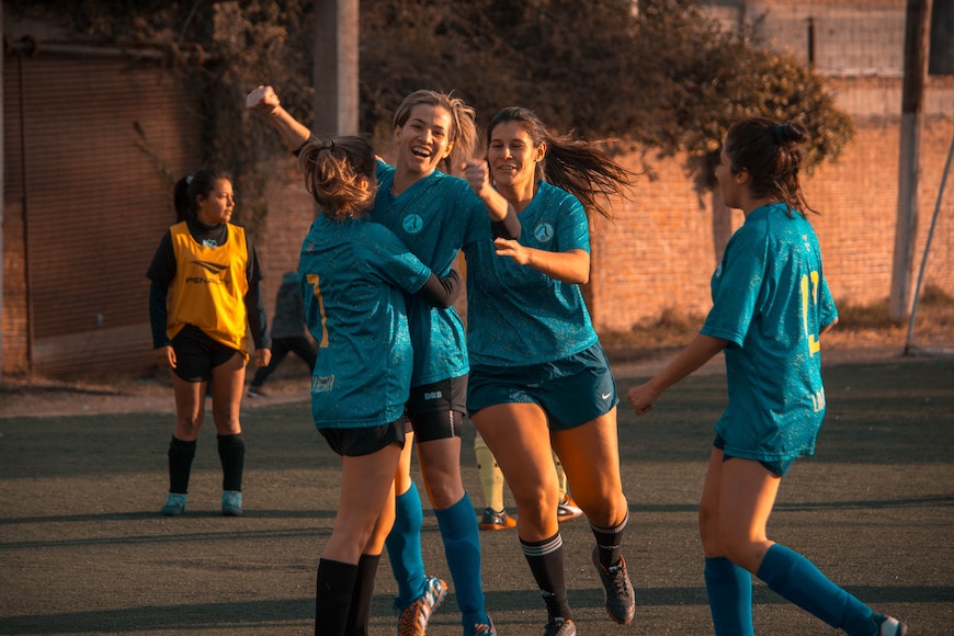 A group of girls playing soccer on a field.