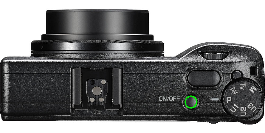 A black digital camera with a green button.