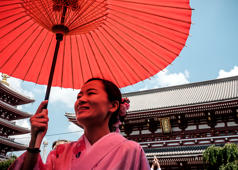 A woman in a kimono holding a red umbrella.