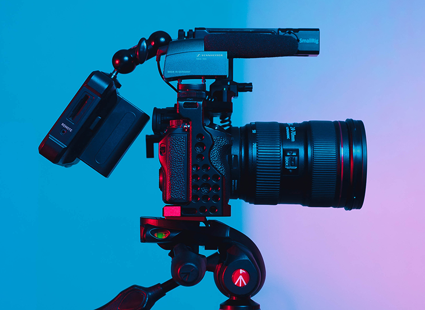 A camera on a tripod in front of a colorful background.