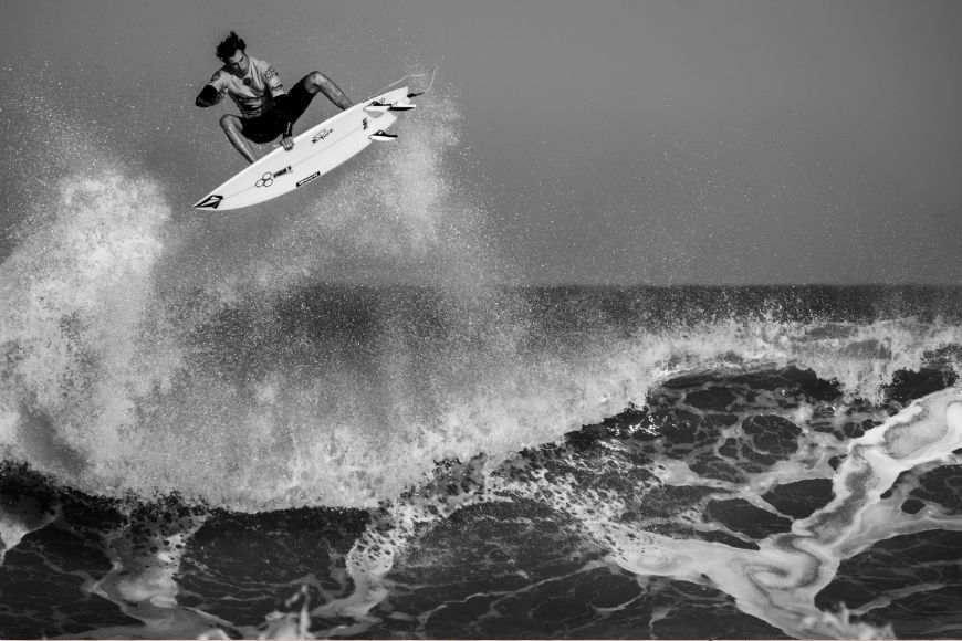 A black and white photo of a surfer in the air.