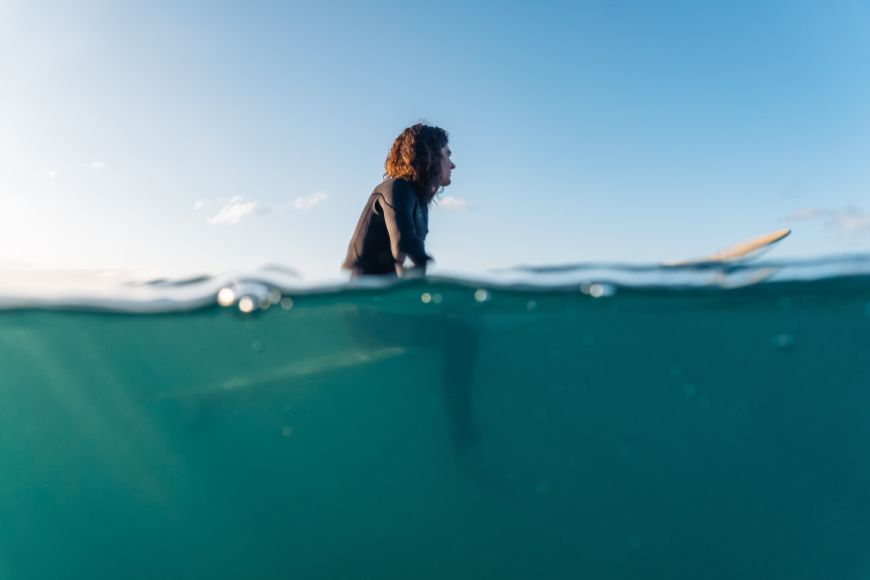 A woman in a wetsuit is riding a surfboard in the ocean.