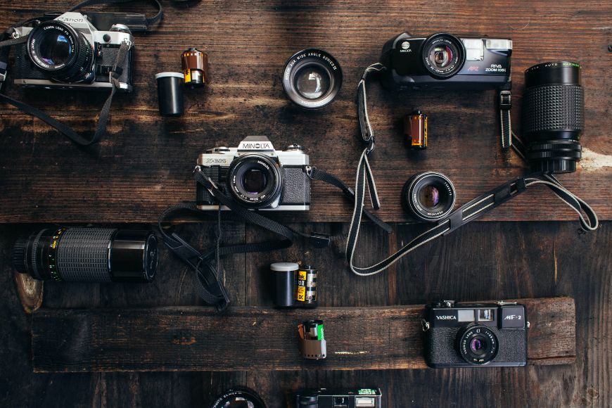 A group of old cameras on a wooden table.