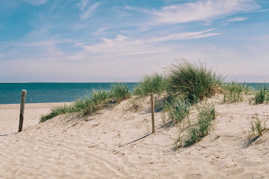 Sand dunes on a beach with a blue sky.