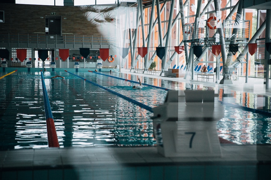 An indoor swimming pool with several swimmers in it.