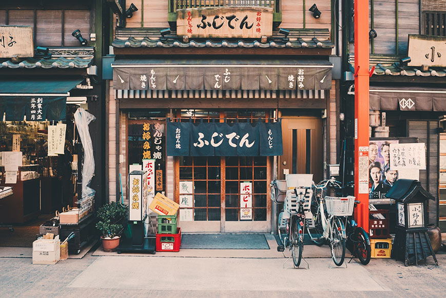 A bicycle is parked in front of a japanese shop.