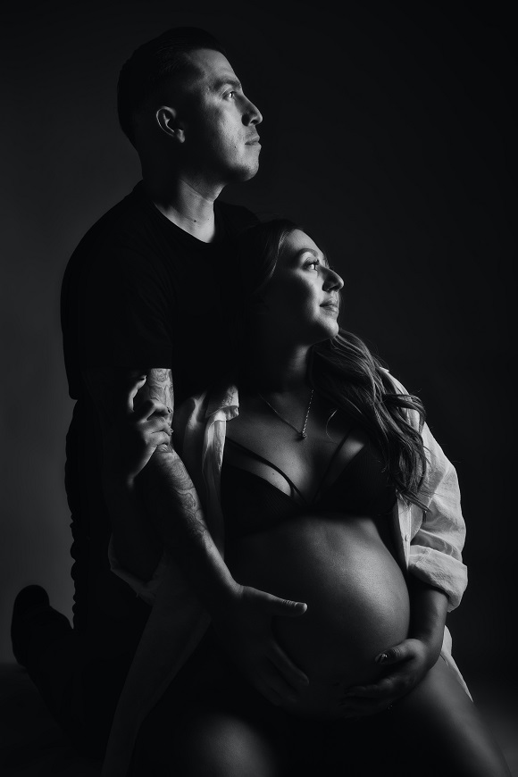 A black and white photo of a couple posing for a maternity photo.