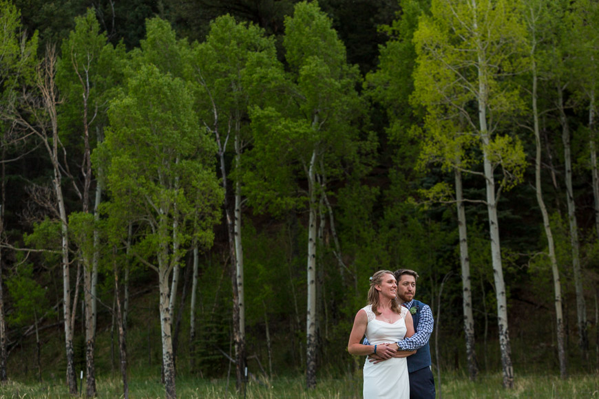 A bride and groom standing in the middle of a wooded area.