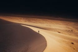 A person walking on a sand dune in the desert.