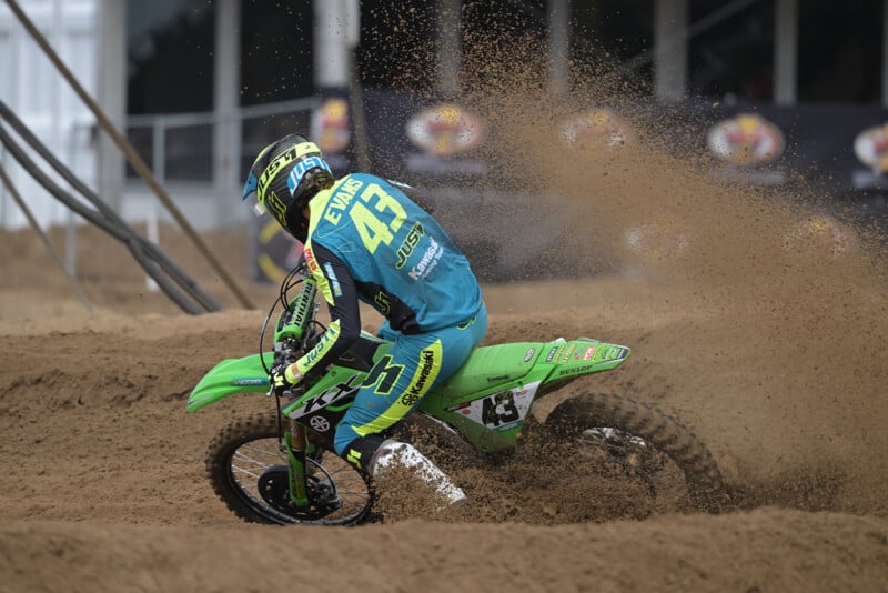 A person riding a green dirt bike on a dirt track.