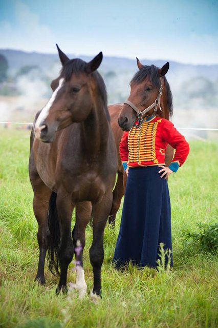 A woman is standing next to two horses in a field.