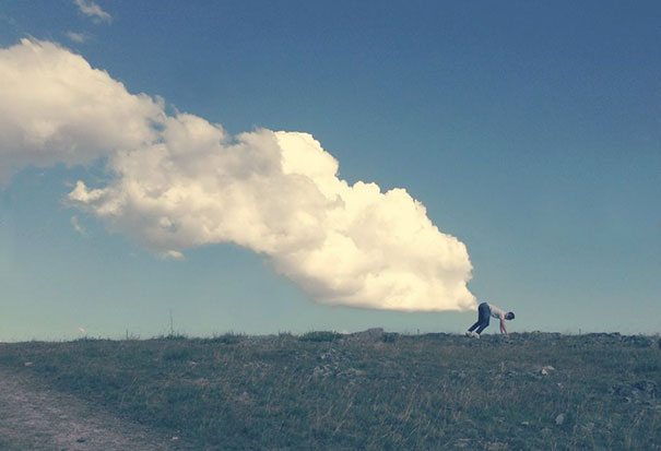 A person standing on a hill with a cloud in the sky.