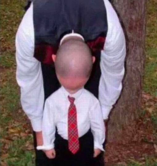 A man in a suit and tie standing next to a little boy.