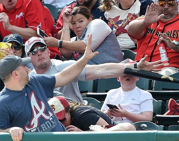 A group of people watching a baseball game with a man holding a bat.