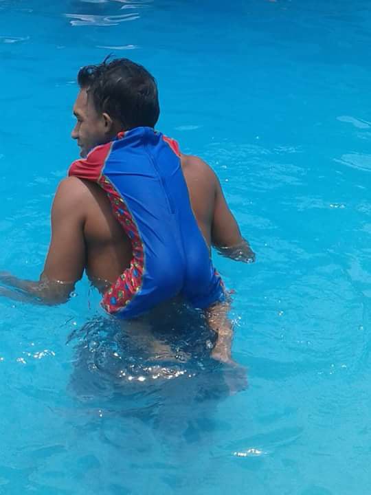 A man carrying a child in a swimming pool.