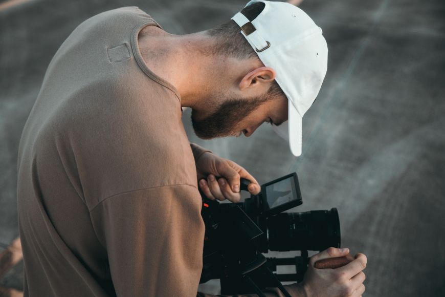 A man in a hat is holding a camera.