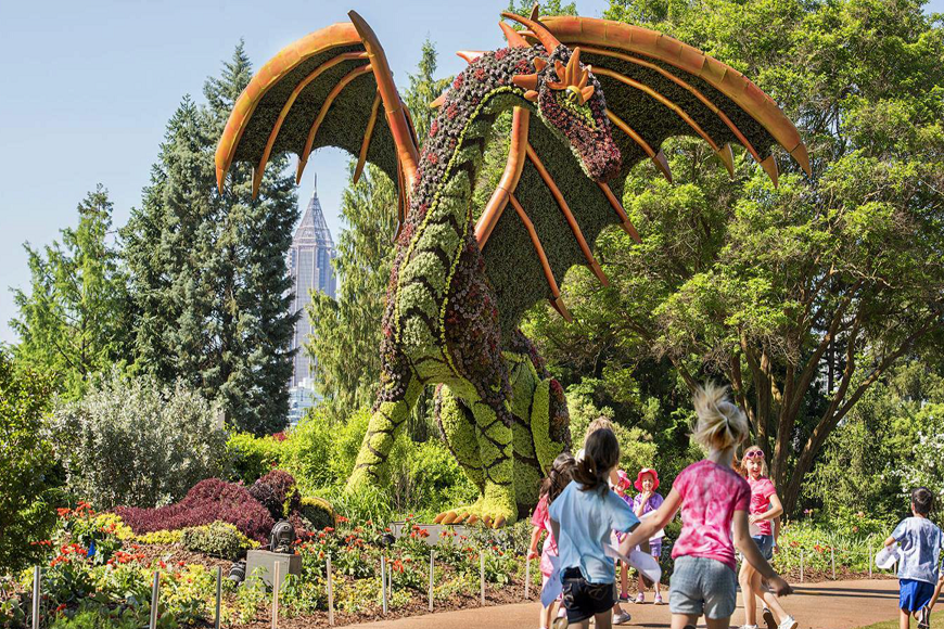 A group of children walk past a large dragon sculpture.