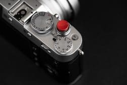 A close up of a silver camera with a red button.