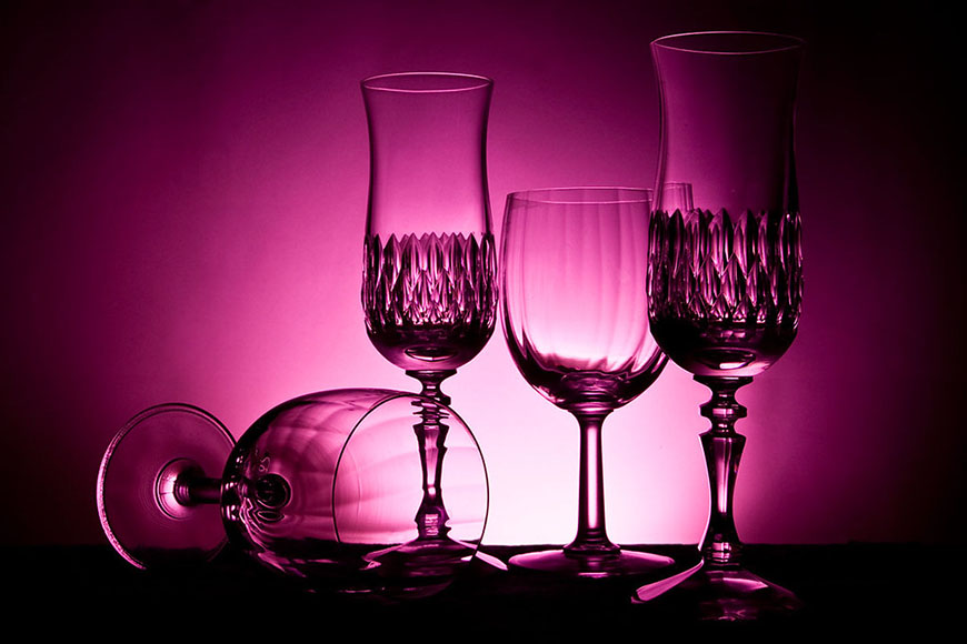 Three wine glasses in front of a purple light.