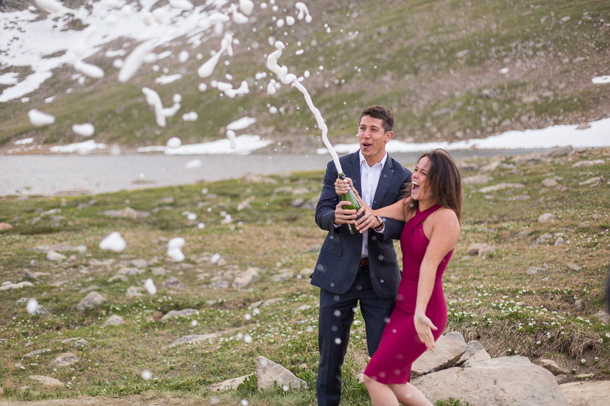 A couple blowing bubbles in front of a mountain.