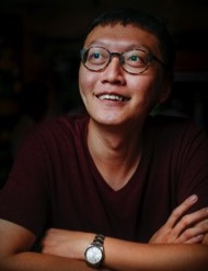 An asian man wearing glasses and a burgundy shirt.