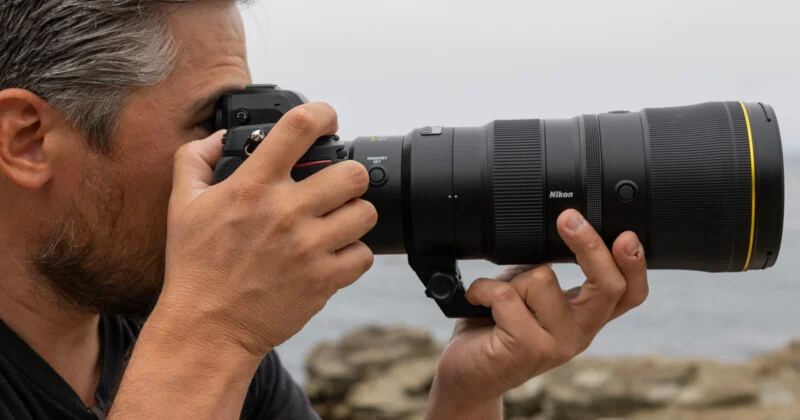 A man is taking a picture with a large lens.