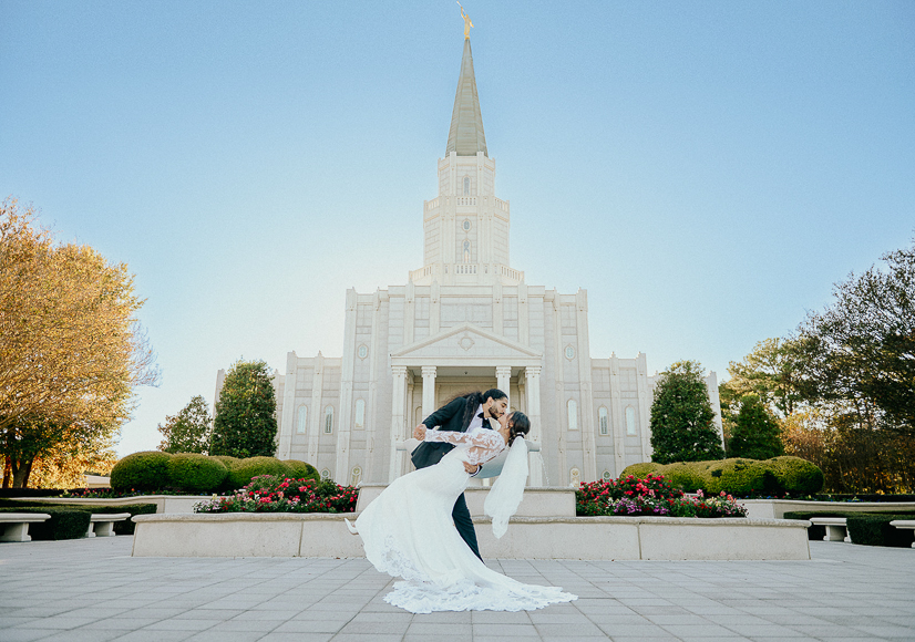 A bride and groom kissing in front of the mormon temple.