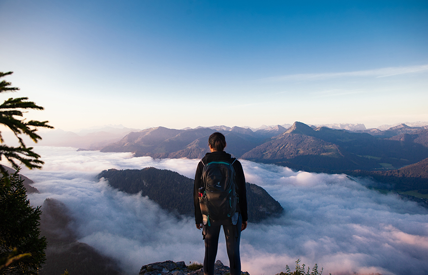 A man standing on top of a mountain overlooking the clouds.