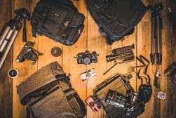 Photography equipment and bags arranged on a wooden floor.