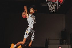 A basketball player in mid air dunks a basketball.