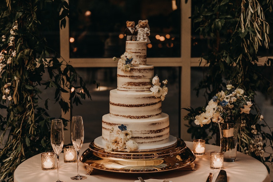A wedding cake sitting on a table in front of a window.