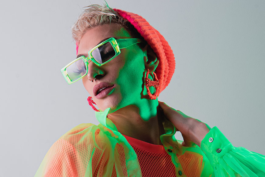 A woman wearing neon glasses and a neon hat.