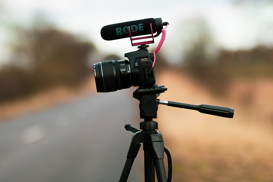 A camera on a tripod with a microphone on it.