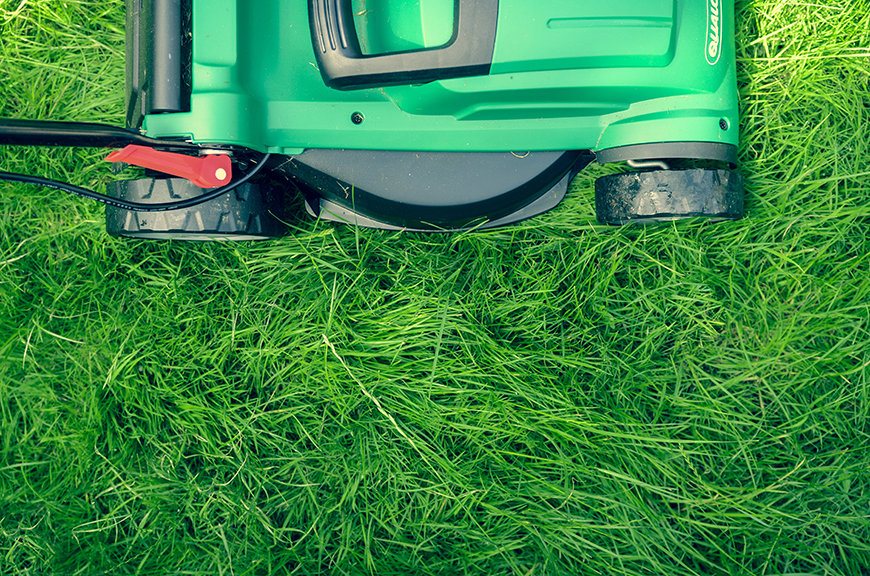 A green lawn mower laying on the grass.
