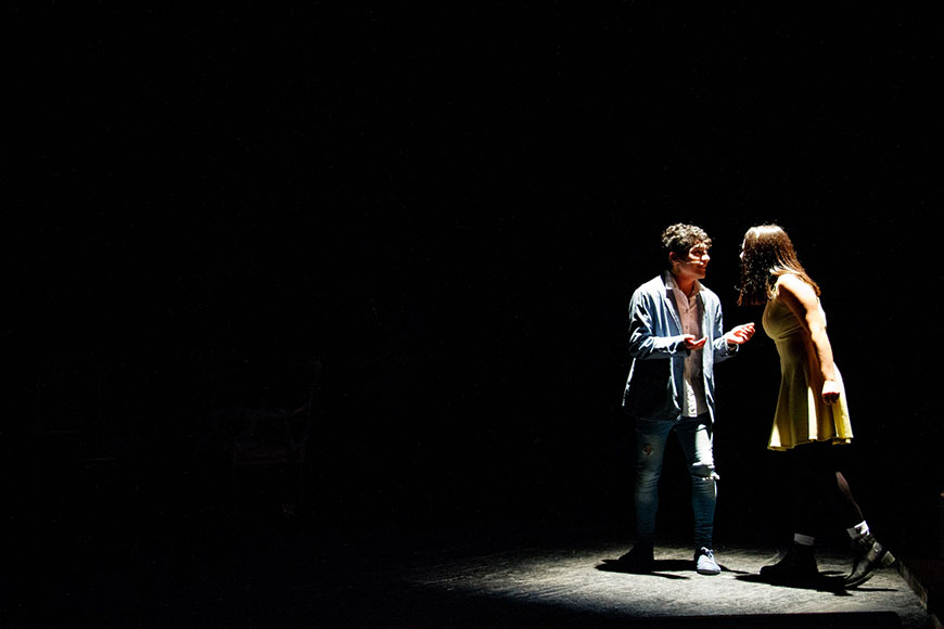 Two people standing on a stage in the dark.