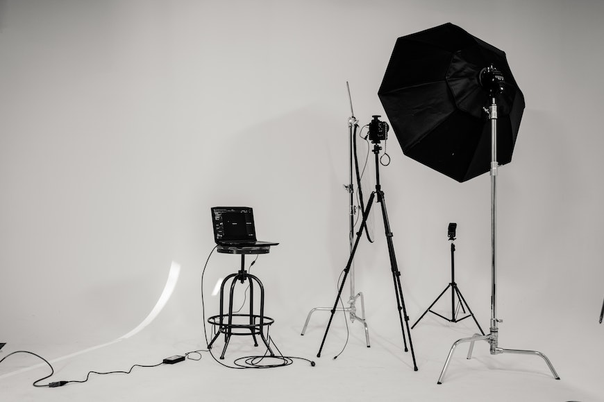 A black and white photo studio with a tripod, lights, and a camera.