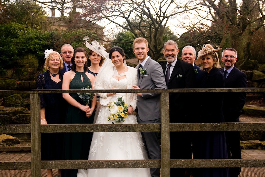 A wedding party posing for a picture on a bridge.