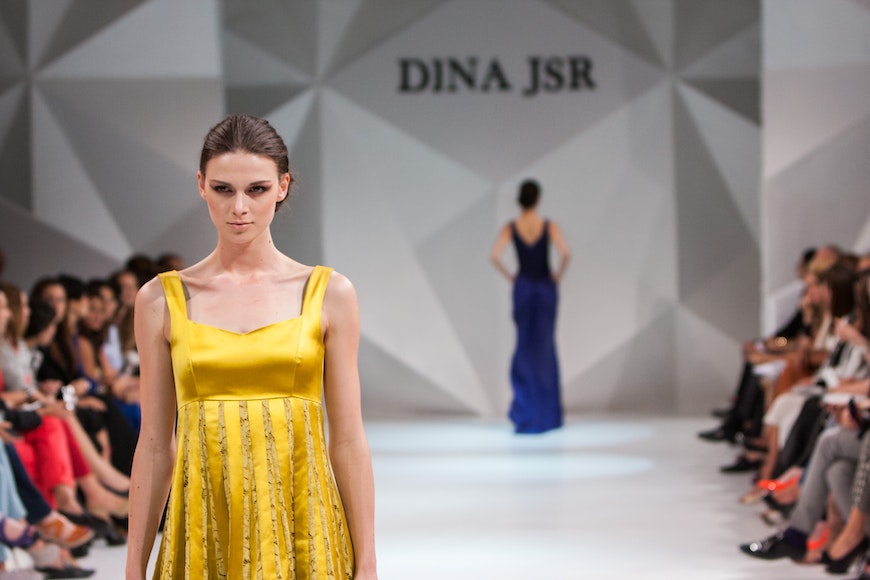 A woman in a yellow dress walks down the runway.