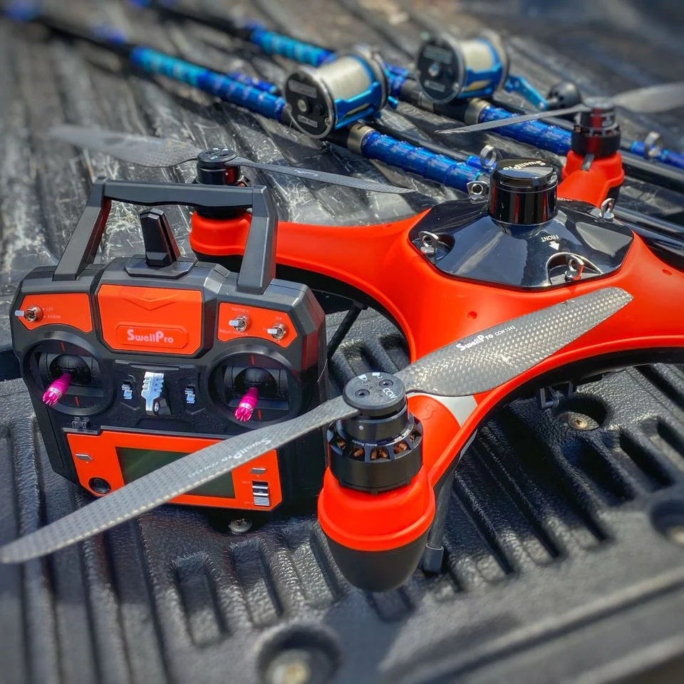 A red and orange drone sits in the bed of a pickup truck.