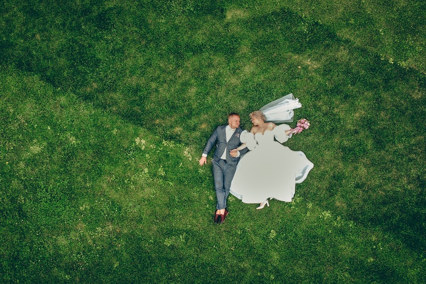 An aerial view of a bride and groom in the grass.