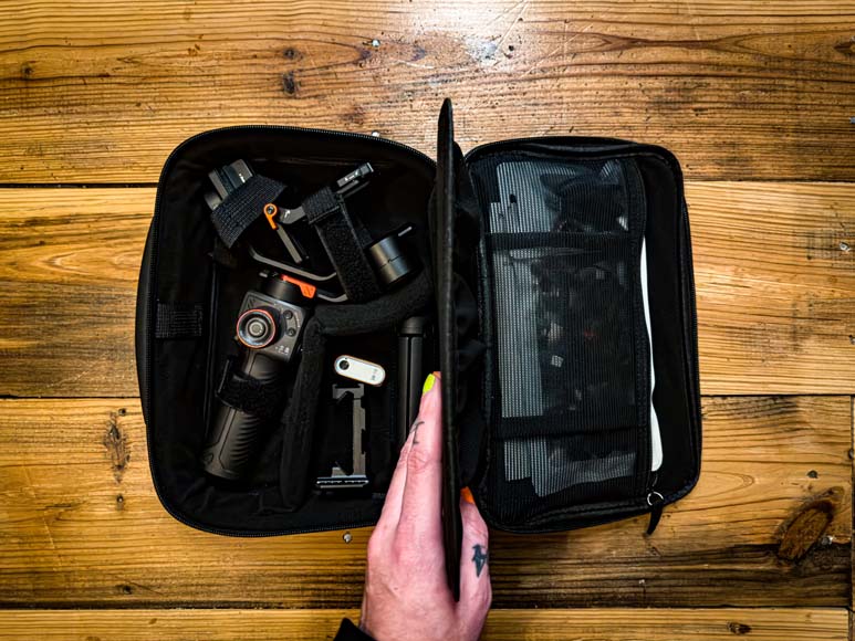 A person's hand holding a camera bag full of equipment.