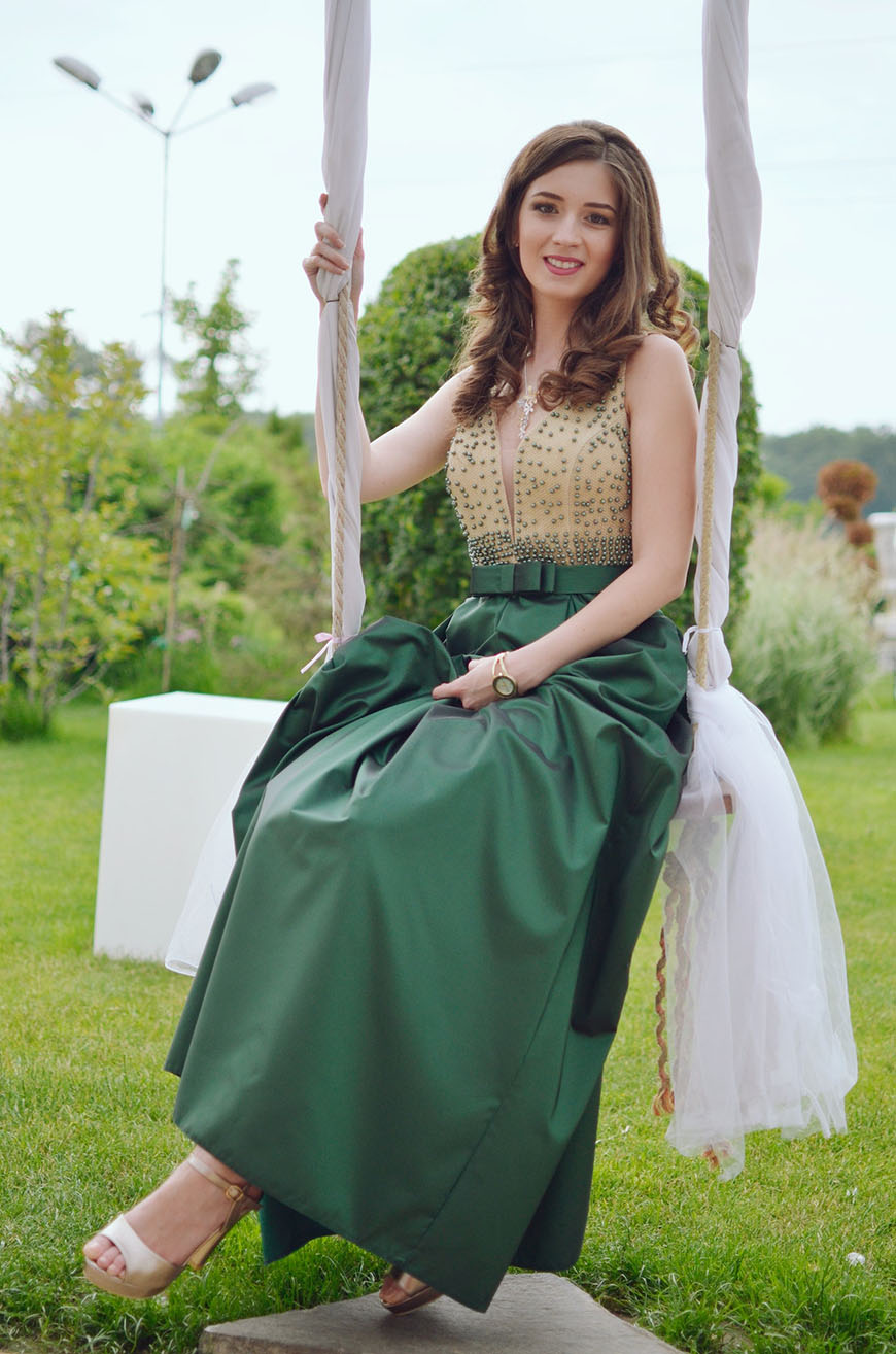A woman in a green dress sitting on a swing.