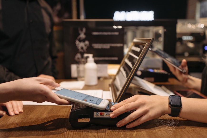 A person is using a smartphone to pay at a coffee shop.