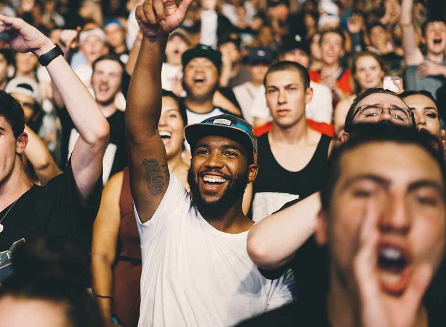 A crowd of people cheering at a concert.