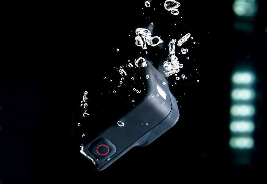 A cell phone with water splashing on it.