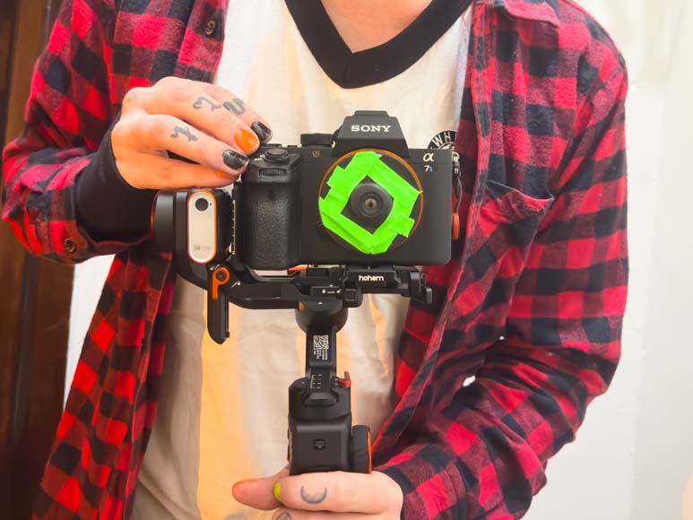 A person holding up a camera with a green circle on it.