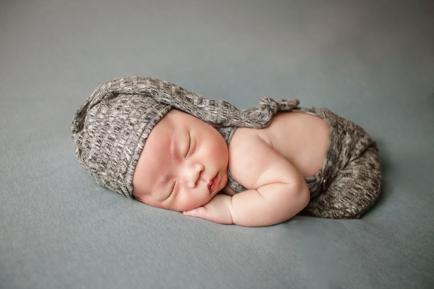 A newborn baby sleeping on a grey background.
