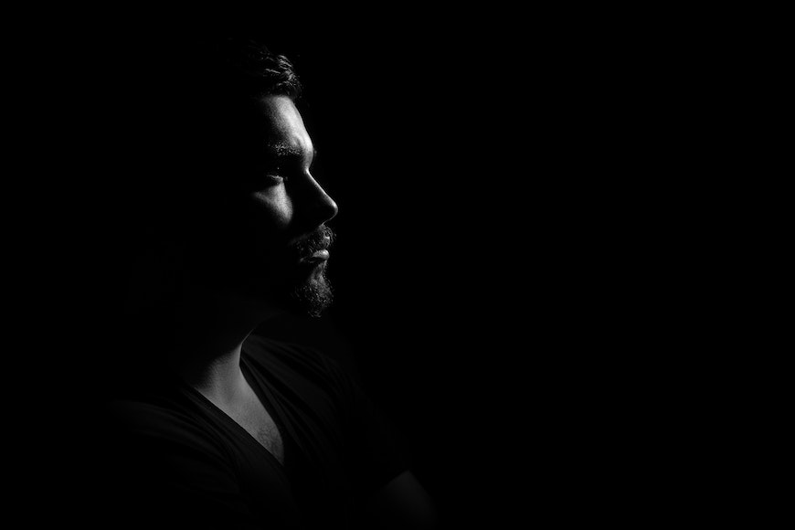A man is silhouetted against a black background.