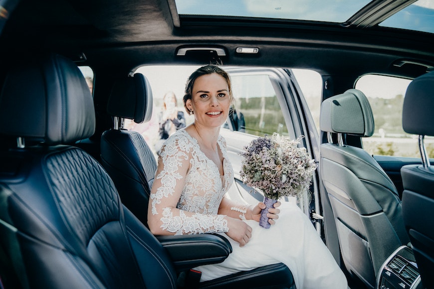 A bride sitting in the back seat of a car.