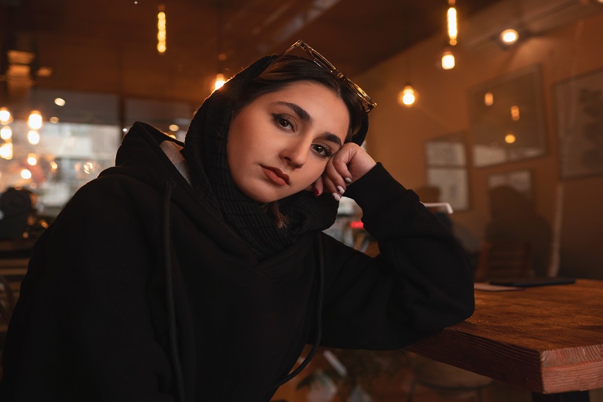 A woman in a black hoodie sitting at a table.